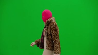 Pembe kar maskeli kadın, kaplan kürkü manto ve gece elbisesi yürüyüşü. Stüdyoda yeşil arka plandaki kadın ucubesi. Moda eğilimi kavramı, feminist moda eğilimi