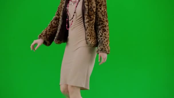 身穿虎皮大衣和晚礼服的女人走路 工作室里的女性对绿色背景非常好奇 时尚潮流理念 女权主义潮流在时尚半圈 — 图库视频影像