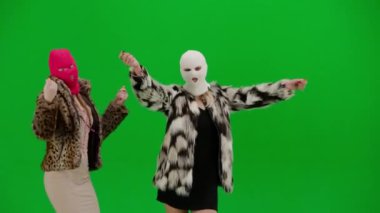 Beyaz ve pembe kar maskeli iki kadın neşeyle dans ediyor. Yeşil stüdyo arka planında kürk giyen ucube kadınlar. Moda eğilimi, feminist moda eğilimi