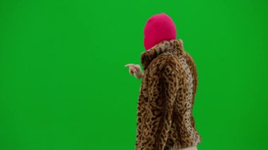 Pembe kar maskeli kadın, kaplan ceketli ve gece elbisesi giyen kadın sanal ekranda geziniyor. Stüdyoda yeşil arka plandaki ucube kadın. Moda eğilimi, feminist moda eğilimi