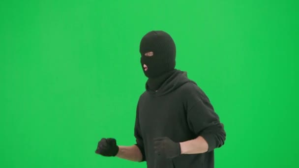 強盗と犯罪概念 クロマキーグリーンの背景に泥棒の肖像画 フーディー ジーンズ 黒いバラバラを身に着けている男の強盗は 犯罪を犯す準備をしている ハーフターン — ストック動画