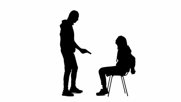 白い隔離された背景に泥棒と犠牲者の黒いシルエット 椅子に座っている少女は 手を縛られ 銃で強盗を盗み 彼女を脅かします — ストック動画