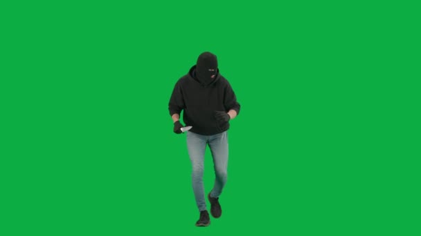 抢劫和犯罪概念 色键绿色屏幕背景上的小偷肖像 穿着巴拉克拉瓦和帽衫的男子劫匪手拿着刀环顾四周 — 图库视频影像