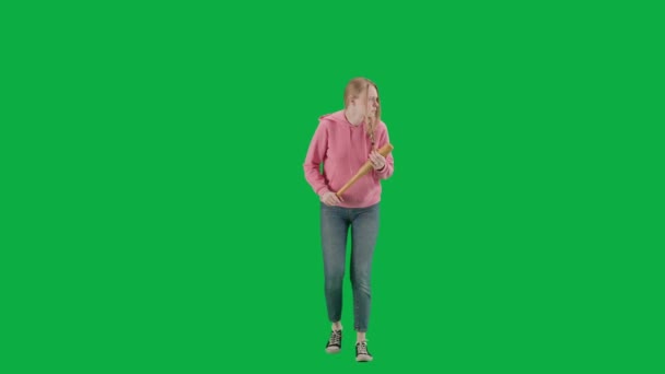 強盗と犯罪概念 クロマキーの緑色の背景の犠牲者の肖像画 一人で歩いている若い女の子 怖い顔の表情 野球のバットを持って 周りを見回して — ストック動画