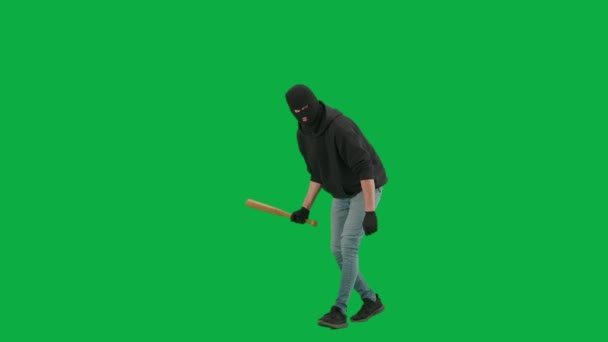 抢劫和犯罪概念 色键绿色屏幕背景上的小偷肖像 身穿巴拉克拉瓦和帽衫的男子抢劫犯手牵着棒球棒走来走去 环顾四周 转半圈 — 图库视频影像