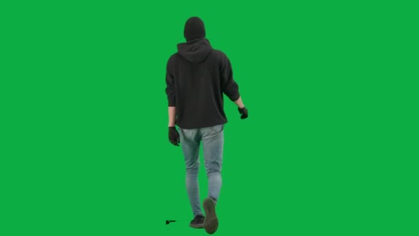 強盗と犯罪概念 クロマキーグリーンの背景に泥棒の肖像画 フーディー ジーンズ 黒いバラバラを身に着けている男の強盗は 犯罪の準備をするために歩いている バックビュー — ストック動画
