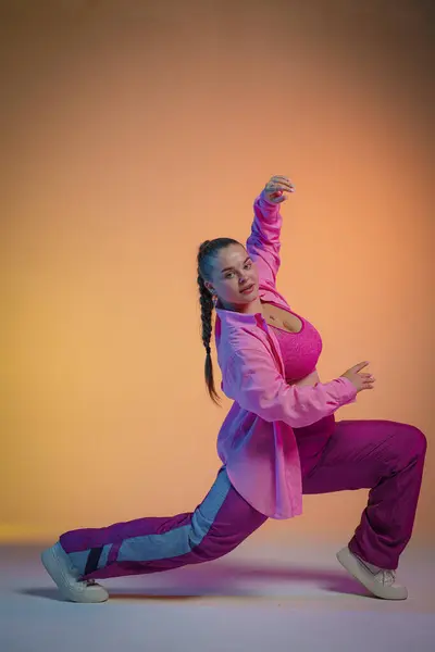 Young Woman Pink Shirt Poses Orange Studio Background Dancer Demonstrates — Stock Photo, Image