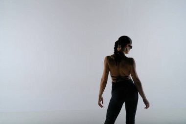 Siyah elbiseli genç bir kadın beyaz stüdyo arka planında poz veriyor. Dişi dansçı poz verir ve ince vücudunu gösterir. Dans tanıtım çekimi konsepti