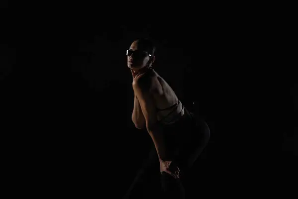 身穿黑色紧身衣和紧身衣的年轻女子在黑背光工作室的背景下摆姿势 女舞蹈演员在高跟鞋上表演舞蹈元素 舞蹈宣传视频概念 — 图库照片