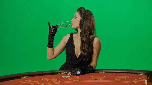 カジノとギャンブルの商業広告コンセプト クロマキーグリーンスクリーンのスタジオの女性が閉じます ブラックジャックポーカーテーブルの黒いドレスの女性は シャンパンのグラスを飲んで ポーズ — ストック写真