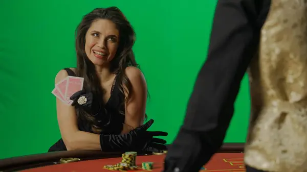 赌场和赌博商业广告的概念 漂亮的女性在工作室的彩色键绿色屏幕上 穿着衣服的女人和蹲在21点扑克桌旁笑的男人 — 图库照片