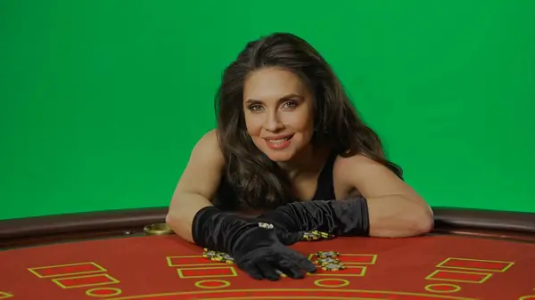 カジノとギャンブルの商業広告コンセプト クロマキーグリーンスクリーンのスタジオの女性は背景を隔離しました ブラックジャックのテーブルで黒いドレスを着た女性が笑顔でチップを獲得 — ストック写真