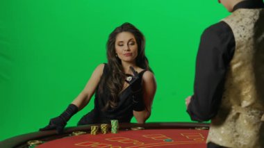 Kumarhane ve kumar yaratıcı reklam konsepti. Krom anahtar yeşil ekranda kadın portresi. Blackjack poker masasında oturan kadın, erkek krupiyeyle oynuyor. Krupiye kartları alıyor ve bahis oynuyor..