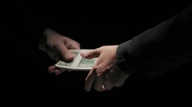 İş ortaklığı ve para yozlaşması yaratıcı kavram. Siyah arka planda izole edilmiş takım elbiseli iş adamlarının portresi. Ortak, iş arkadaşına tokalaşmak için bir tomar para veriyor..