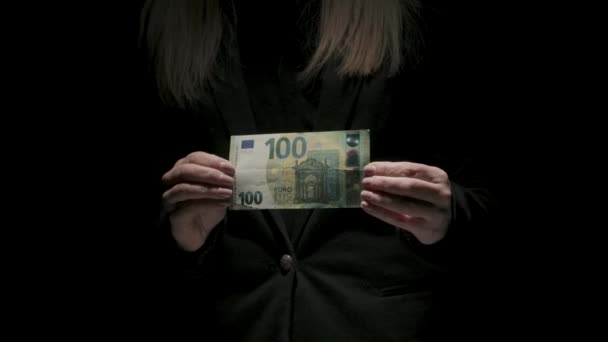 ビジネスとマネーのクリエイティブ広告コンセプト 黒いバックグラウンドで隔離された黒いスーツの女性の肖像画 カメラで百ユーロ紙幣を手に持っている女性 — ストック動画