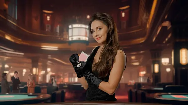 Chic woman in black dress at poker table for blackjack game in casino. Woman holding poker playing cards and looking at camera. The concept of casino and gambling