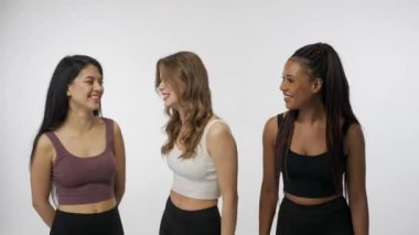 Doğal güzellik ve çeşitlilik reklam konsepti. Beyaz arka planda çok ırklı genç modellerin portresi. Üç güzel çok ırklı kız grubu kamera karşısında şakalaşıyor ve konuşuyor.