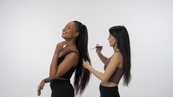自然美と多様性の広告コンセプト 白いスタジオの背景に孤立した若い多民族モデルの肖像画 2人のポジティブな多人種間の女の子のグループはお互いの髪をブラッシング — ストック動画
