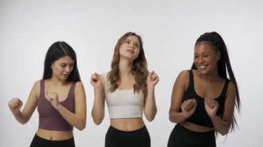 Doğal güzellik ve çeşitlilik reklam konsepti. Beyaz stüdyo arka planında çok ırklı genç modellerin portresi yakın plan. Üç güzel çok ırklı kız grubu kameranın karşısında mutlu bir şekilde dans ediyor.