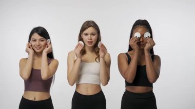 Doğal güzellik ve çeşitlilik reklam konsepti. Beyaz stüdyo arka planında çok ırklı genç modellerin portresi yakın plan. Pamuk disklerle kameraya poz veren üç çok ırklı kız grubu.