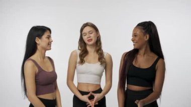 Doğal güzellik ve çeşitlilik reklam konsepti. Beyaz stüdyo arka planında çok ırklı genç modellerin portresi yakın plan. Üç kişilik bir grup, kameraya gülümseyen çok ırklı kızları cezbediyor.