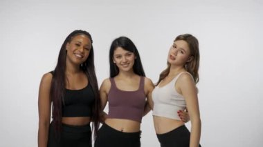 Doğal güzellik ve çeşitlilik reklam konsepti. Beyaz stüdyo arka planında çok ırklı genç modellerin portresi yakın plan. Üç kişilik bir grup çok ırklı kız kameraya sarılıp gülümsüyor.