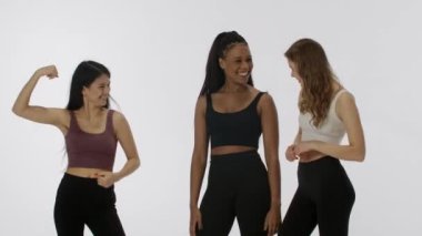 Doğal güzellik ve çeşitlilik reklam konsepti. Beyaz stüdyo arka planında izole edilmiş genç çoklu etnik modellerin portresi. Üç pozitif çok ırklı kızdan oluşan bir grup şaka yapıyor. Kameraya kaslarını göster.