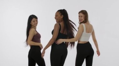 Doğal güzellik ve çeşitlilik reklam konsepti. Beyaz stüdyo arka planında izole edilmiş genç çoklu etnik modellerin portresi. Kameraya sırtüstü poz veren üç pozitif çok ırklı kız grubu.