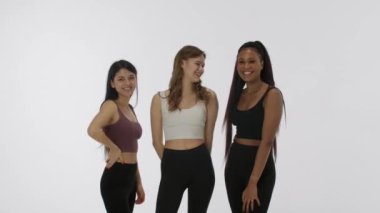 Doğal güzellik ve çeşitlilik reklam konsepti. Beyaz arka planda izole edilmiş genç çoklu etnik modellerin portresi. Üç pozitif çok ırklı kız grubu kameraya el sallıyor ve gülümsüyor.