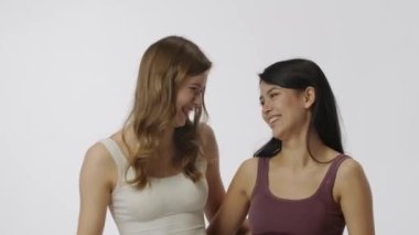 Doğal güzellik ve çeşitlilik reklam konsepti. Beyaz arka planda izole edilmiş çok ırklı modellerin portresi, yakın çekim. Kameraya sarılarak poz veren iki çok ırklı kız grubu.