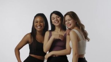 Doğal güzellik ve çeşitlilik reklam konsepti. Beyaz arka planda izole edilmiş çok ırklı modellerin portresi, yakın çekim. Üç tane çok ırklı genç kız grubu kameranın önünde eğleniyor.