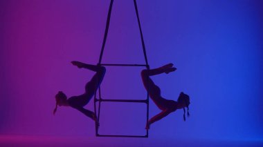 Modern koreografi ve akrobasi yaratıcı reklam konsepti. Neon arka planda izole edilmiş iki kadın akrobatın silueti. Kız akrobat dansçılar iplerle havada yarık açıyorlar..