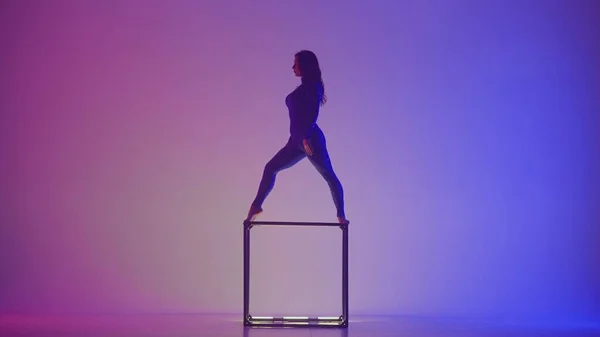 现代编舞和杂技创意广告的概念 在蓝色紫色霓虹灯背景下孤立的女性杂技演员的轮廓 身穿紧身衣的女子体操运动员在立方体上表演 — 图库照片