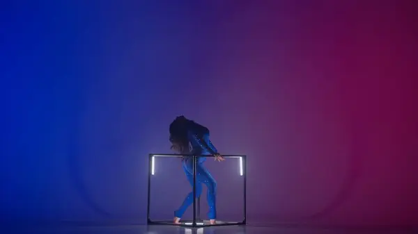 现代编舞和杂技创意广告的概念 女性杂技演员在霓虹灯背景下被隔离的轮廓 身穿蓝色闪亮紧身衣的女子体操舞者在立方体上分叉 — 图库照片