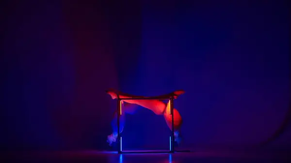 Modern choreography and acrobatics creative advertisement concept. Silhouette of two female acrobats isolated on neon background. Girls gymnastic dancers performing mirrored element on a cube.