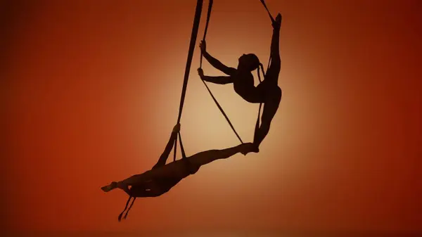 现代编舞和杂技创意广告的概念 两名女杂技演员在橙色霓虹灯背景下被隔离的轮廓 在绳子上表演杂技分裂的女空中舞者 — 图库照片