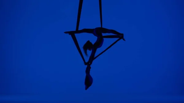 现代编舞和杂技创意广告的概念 在蓝色霓虹灯工作室背景上孤立的女性艺术家的轮廓 在空气绸缎上表演分部分飞行的女空中舞者 — 图库照片