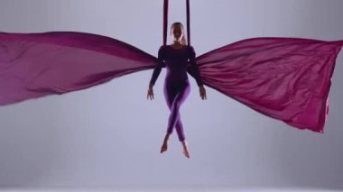 Modern koreografi ve akrobasi yaratıcı reklam konsepti. Mavi neon stüdyo arka planında izole edilmiş kadın sanatçı. Kız dansçı hava ipeği üzerinde süzülüyor..