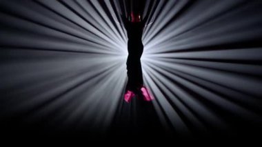 Modern koreografi ve akrobasi yaratıcı reklam konsepti. Parlak spot ışıklarına karşı siyah arkaplanda izole edilmiş bir kadın silueti. İpek üzerinde yürüyen bir kız dansçı..