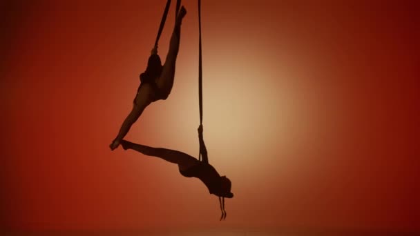 现代编舞和杂技创意广告的概念 两名女杂技演员在橙色霓虹灯背景下被隔离的轮廓 女孩空中舞蹈演员在绳子上表演分开的飞行 — 图库视频影像