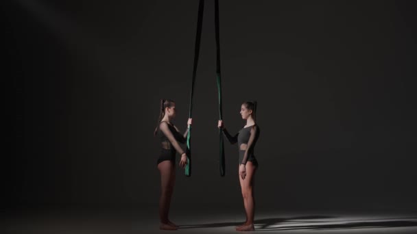 現代の振付とアクロバットクリエイティブ広告コンセプト 黒い背景に隔離された2人の女性のアクロバットの肖像画 ロープでパフォーマンスする準備ができて床に立っている少女空中ダンサー — ストック動画