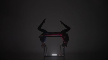 Modern koreografi ve akrobasi yaratıcı reklam konsepti. Siyah arka planda izole edilmiş iki kadın akrobatın portresi. Mavi elbiseli kızlar bir küp üzerinde gösteri yapıyorlar..