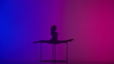Modern koreografi ve akrobasi yaratıcı reklam konsepti. Kadın akrobatın silueti neon arka planda izole edildi. Mavi, ışıl ışıl vücutlu kadın jimnastik dansçısı küpte parçalanmış..