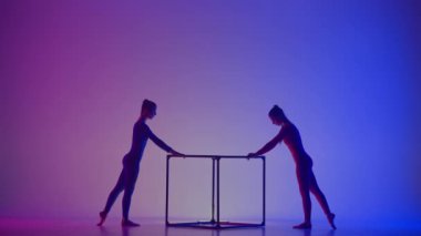 Modern koreografi ve akrobasi yaratıcı reklam konsepti. Canlı arkaplanda izole edilmiş iki kadın akrobatın silueti. Kızlar jimnastik dansçıları küp üzerinde akrobatik hareketler yapıyorlar..