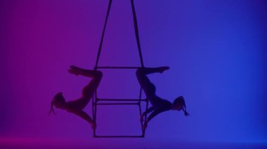 Modern koreografi ve akrobasi yaratıcı reklam konsepti. Neon arka planda izole edilmiş iki kadın akrobatın silueti. Havada iplerle uçan akrobat kızlar..