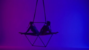 Modern koreografi ve akrobasi yaratıcı reklam konsepti. Neon arka planda izole edilmiş iki kadın akrobatın silueti. Kız akrobat dansçılar iplerle havada yarık açıyorlar..