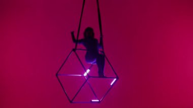Modern koreografi ve akrobasi yaratıcı reklam konsepti. Kırmızı arka planda izole edilmiş kadın akrobat portresi. Kadın akrobatlar havada iplerle ve neon ışıklarla dönüyorlar..