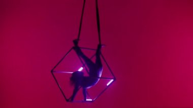 Modern koreografi ve akrobasi yaratıcı reklam konsepti. Kırmızı arka planda izole edilmiş kadın akrobat portresi. Kadın akrobatlar havada iplerle ve neon ışıklarla dönüyorlar..