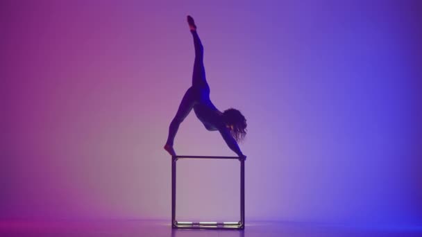 现代编舞和杂技创意广告的概念 在蓝色紫色霓虹灯背景下孤立的女性杂技演员的轮廓 身穿紧身衣的女子体操运动员在立方体上表演 — 图库视频影像