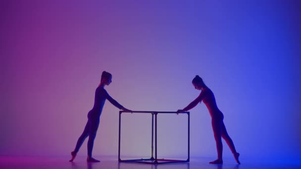 現代の振付とアクロバットクリエイティブ広告コンセプト ネオンの鮮やかな背景に隔離された2人の女性のアクロバットのシルエット キューブでアクロバティックな要素を実行する少女の体操ダンサー — ストック動画
